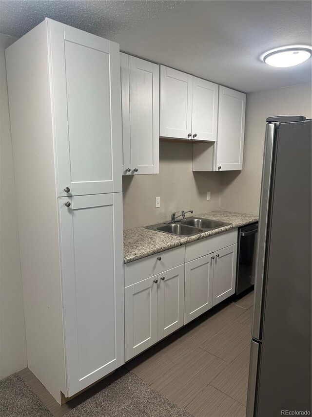 kitchen with stainless steel appliances, a textured ceiling, sink, and white cabinets