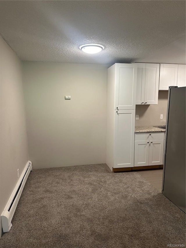 carpeted empty room featuring lofted ceiling, a textured ceiling, and a baseboard heating unit