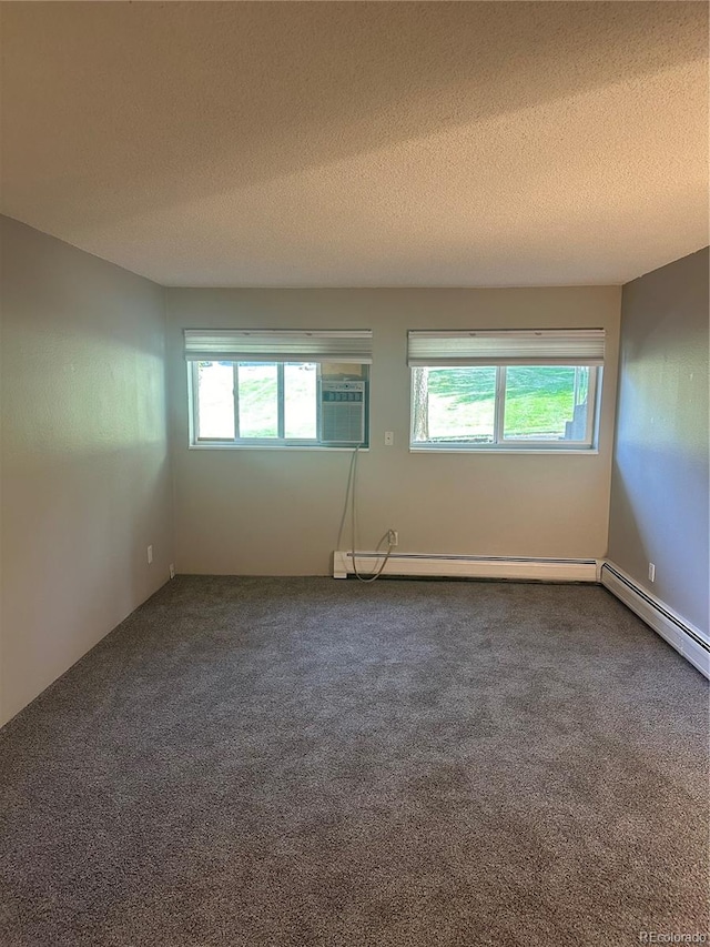 carpeted spare room featuring a healthy amount of sunlight, a textured ceiling, a baseboard heating unit, and a wall unit AC