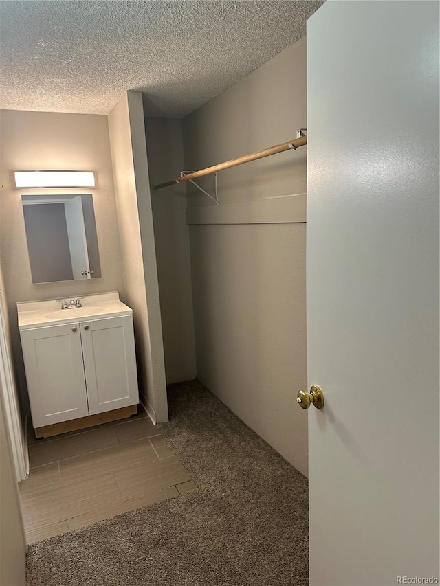 bathroom featuring vanity, wood-type flooring, and a textured ceiling