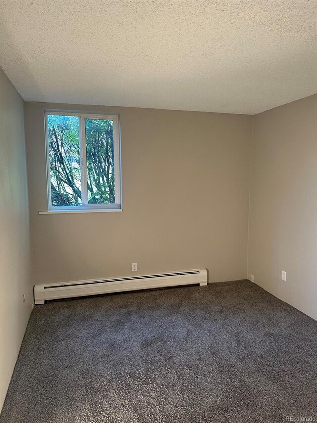 carpeted empty room featuring a baseboard heating unit and a textured ceiling