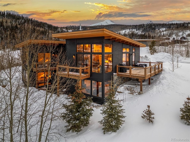 snow covered back of property with a deck with mountain view