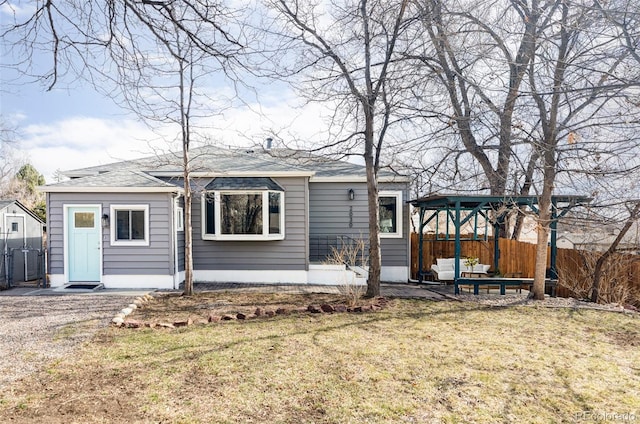 rear view of property featuring a patio area, a lawn, a shingled roof, and fence