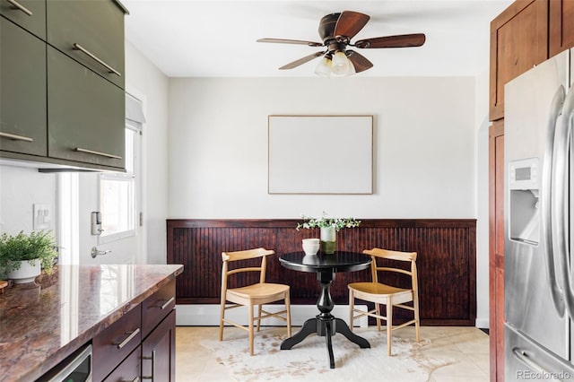 dining space with a wainscoted wall and a ceiling fan