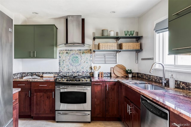 kitchen with appliances with stainless steel finishes, wall chimney exhaust hood, green cabinets, and a sink