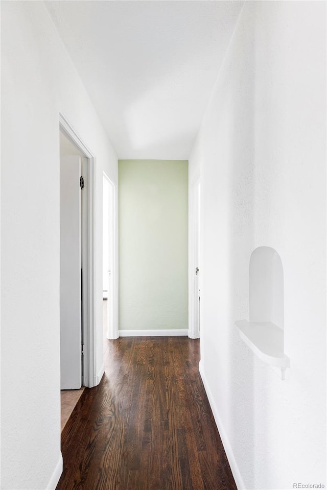 hall featuring baseboards and wood finished floors