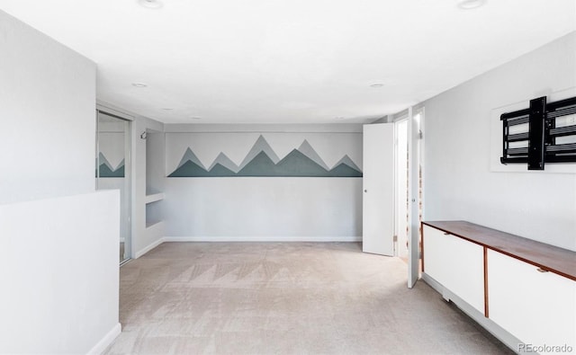 spare room featuring light carpet and baseboards