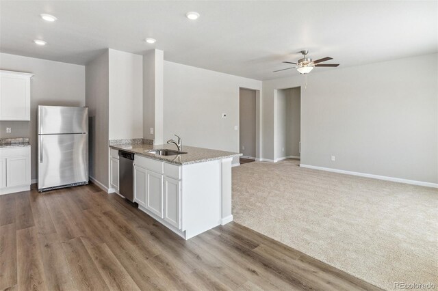 kitchen with light colored carpet, stainless steel appliances, white cabinetry, and sink