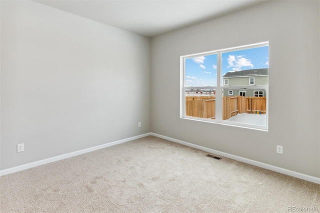 carpeted spare room with visible vents and baseboards