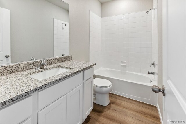 full bathroom featuring hardwood / wood-style floors, toilet, tiled shower / bath combo, and vanity