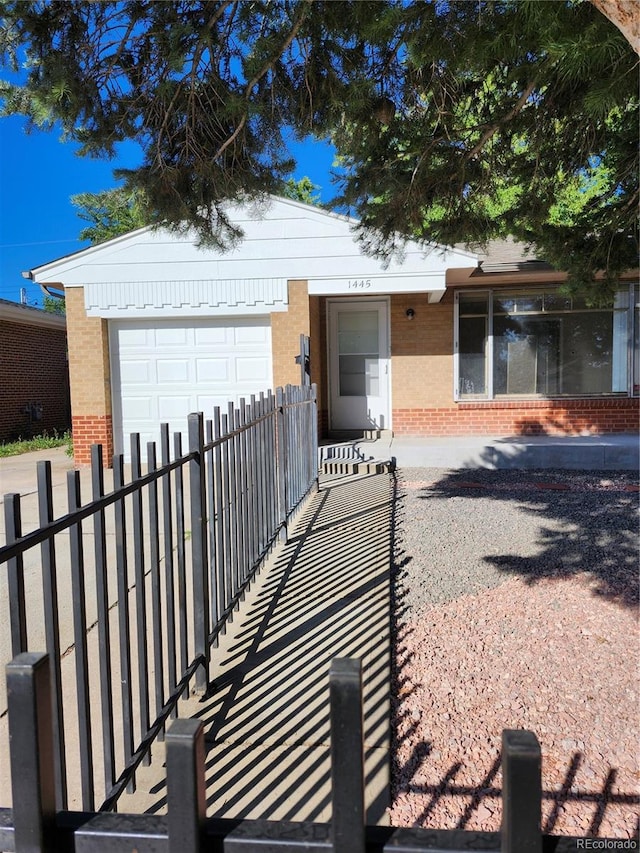 ranch-style home with a fenced front yard, a garage, driveway, and brick siding