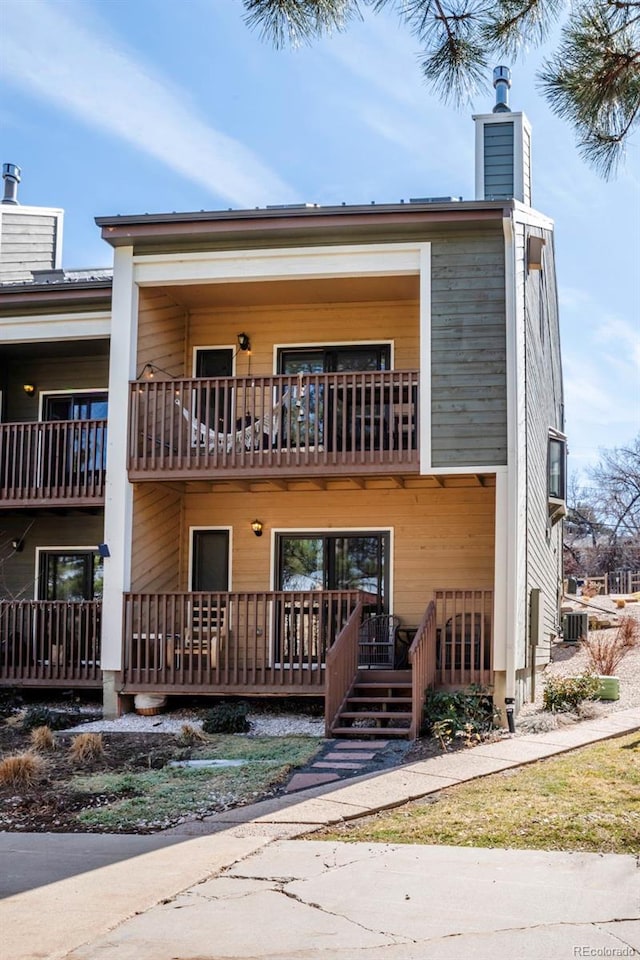 view of front of property with a balcony, central AC unit, and a chimney