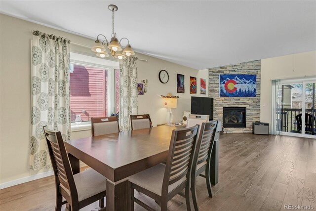 dining area featuring a fireplace, an inviting chandelier, wood finished floors, and baseboards