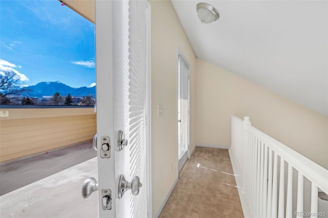 hallway with a mountain view, carpet flooring, and vaulted ceiling