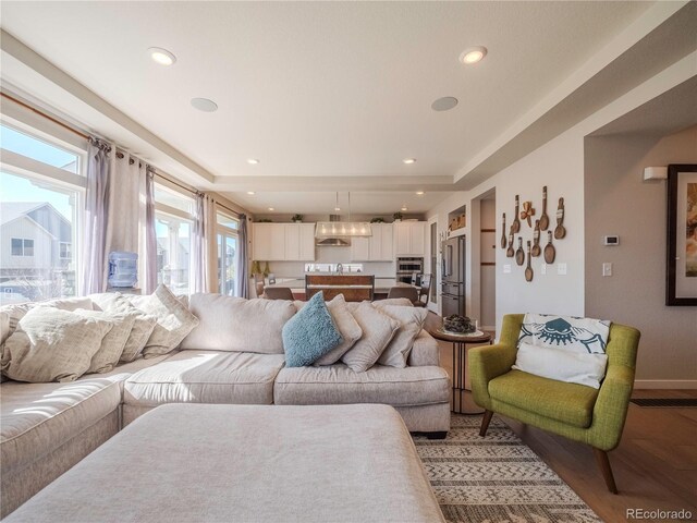 living room with baseboards, wood finished floors, and recessed lighting