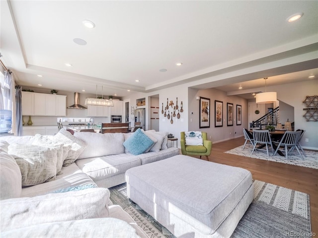 living area featuring light wood-type flooring, baseboards, stairway, and recessed lighting