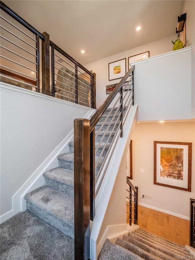 staircase featuring baseboards, wood finished floors, and recessed lighting