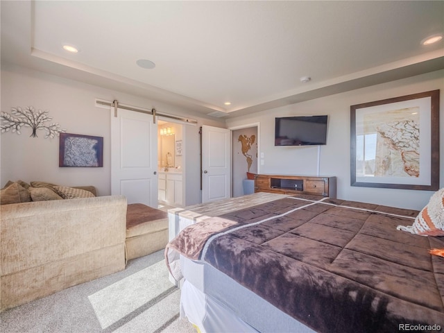 bedroom with a barn door, recessed lighting, carpet floors, a raised ceiling, and ensuite bath