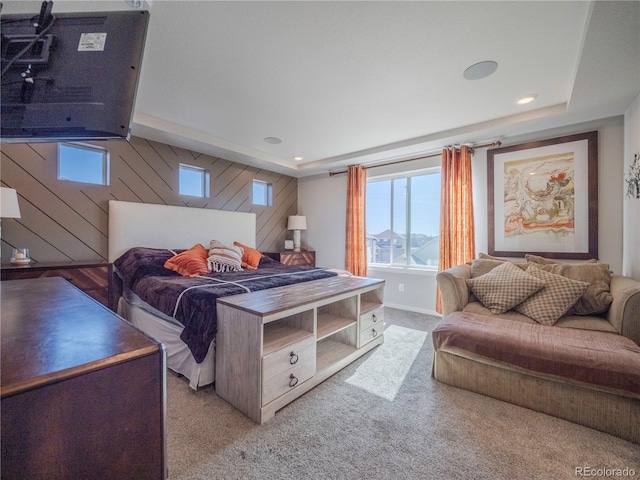 bedroom featuring recessed lighting, wooden walls, a tray ceiling, and light colored carpet