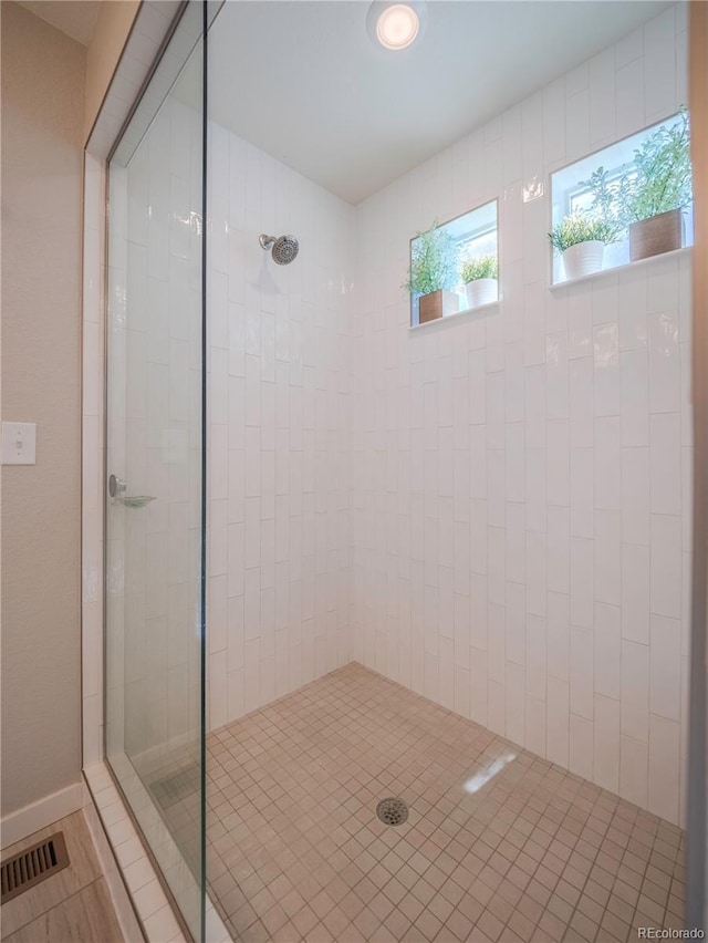 full bath with visible vents and tiled shower