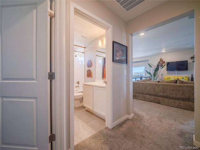 hallway featuring light tile patterned floors, recessed lighting, light carpet, a sink, and visible vents