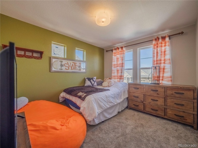 bedroom with multiple windows, light carpet, and a textured ceiling