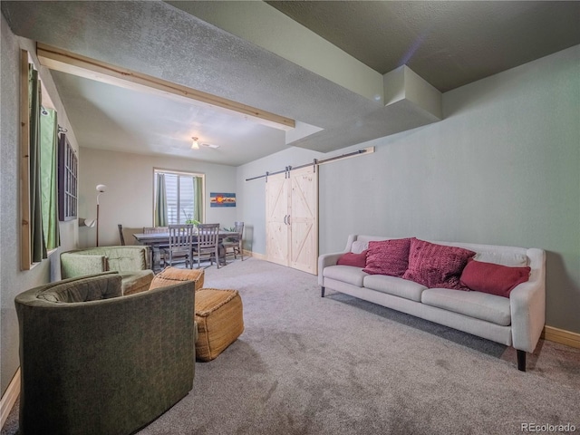 carpeted living room featuring a barn door, baseboards, and a textured ceiling