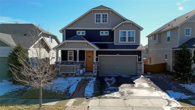 craftsman house featuring driveway, covered porch, a garage, and stone siding