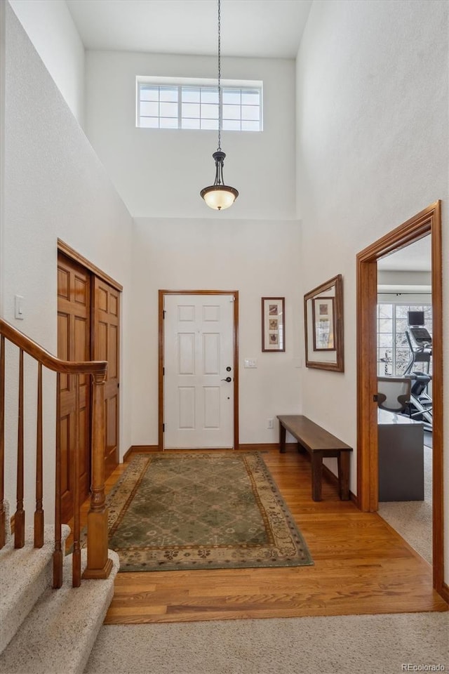 foyer with a wealth of natural light, a high ceiling, stairway, and wood finished floors