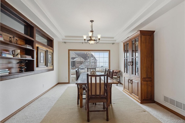 dining area with a raised ceiling, light colored carpet, visible vents, an inviting chandelier, and baseboards