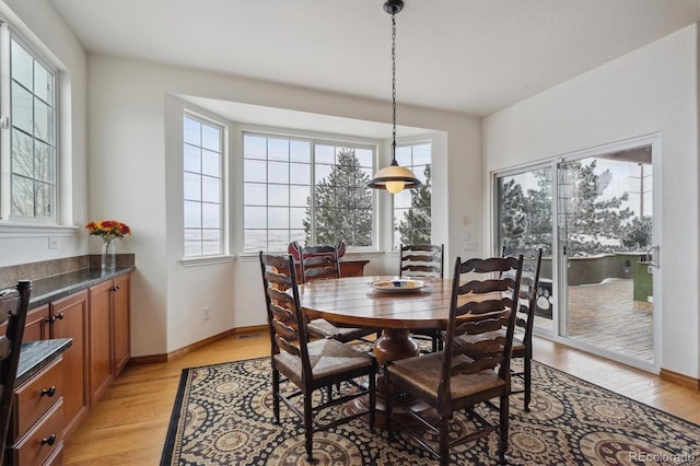 dining space with light wood finished floors and baseboards