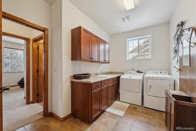 laundry room featuring a sink, visible vents, a healthy amount of sunlight, cabinet space, and washer and clothes dryer