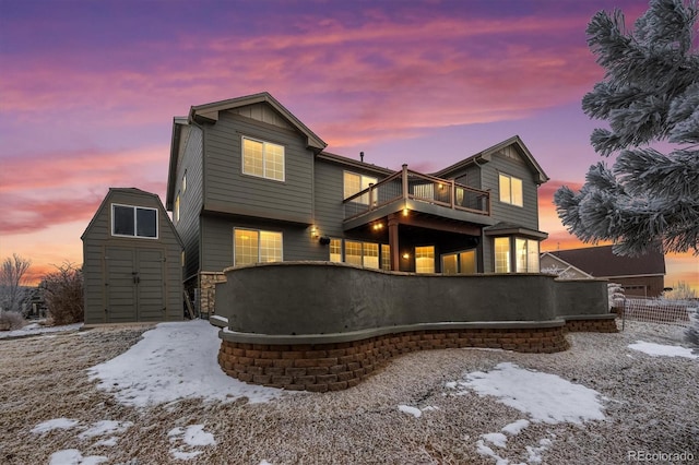 snow covered property with aphalt driveway, an outdoor structure, a balcony, and a storage unit