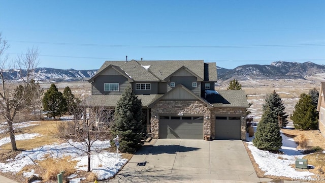 craftsman-style house featuring a garage, concrete driveway, a mountain view, and stone siding