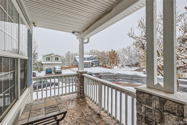 snow covered back of property with covered porch