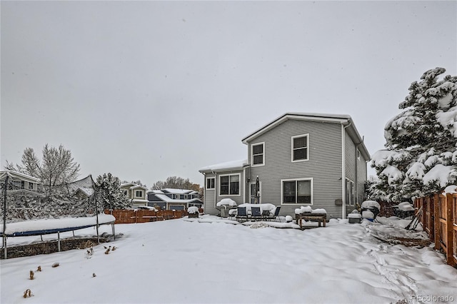 snow covered back of property featuring a trampoline