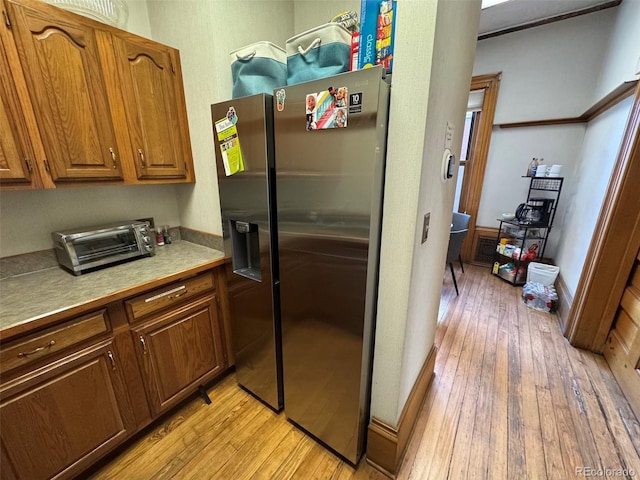 1625 N Downing St, Denver, CO 80218 - kitchen with stainless steel refrigerator with ice dispenser, light wood finished floors, brown cabinetry, and light countertops