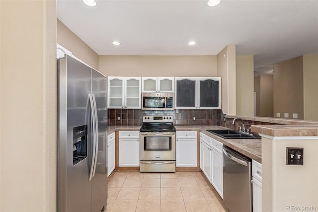 8427 S Hoyt Way Unit 107, Littleton, CO 80128 - kitchen featuring appliances with stainless steel finishes, tasteful backsplash, white cabinets, light tile patterned floors, and glass insert cabinets
