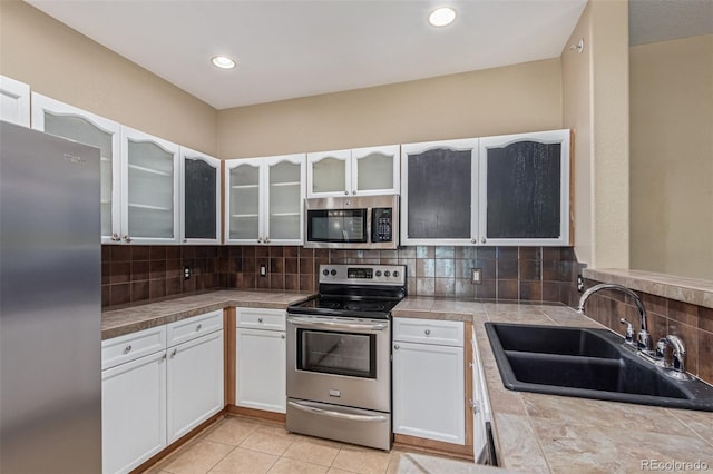 8427 S Hoyt Way Unit 107, Littleton, CO 80128 - kitchen with stainless steel appliances, white cabinetry, decorative backsplash, glass insert cabinets, and recessed lighting