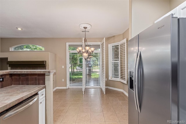 8427 S Hoyt Way Unit 107, Littleton, CO 80128 - kitchen with appliances with stainless steel finishes, white cabinets, a chandelier, light tile patterned floors, and hanging light fixtures