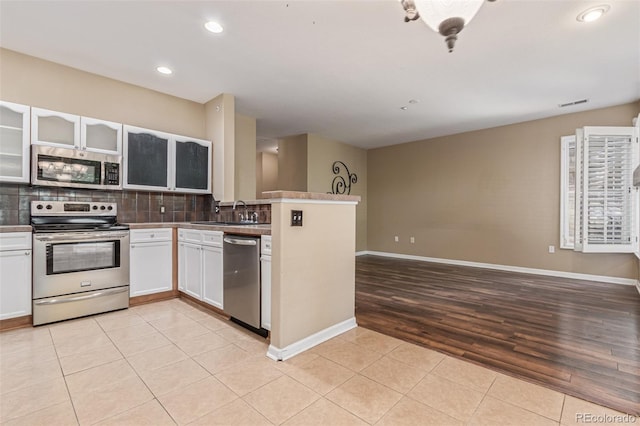8427 S Hoyt Way Unit 107, Littleton, CO 80128 - kitchen featuring stainless steel appliances, backsplash, light tile patterned flooring, open floor plan, and recessed lighting