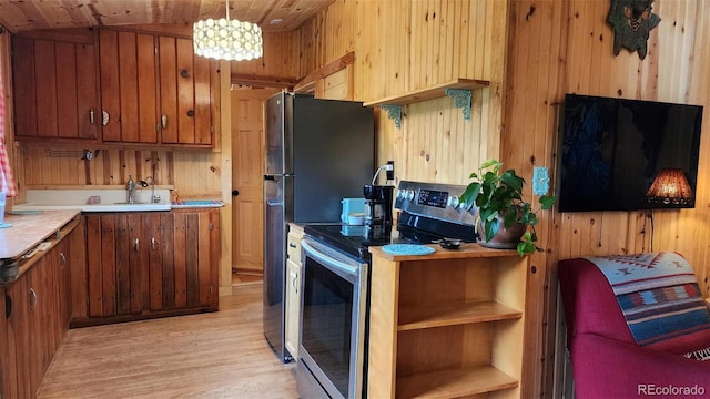 256 Fisk Fenner Rd, Allenspark, CO 80510 - kitchen featuring stainless steel electric range, light wood finished floors, wooden walls, brown cabinetry, and light countertops