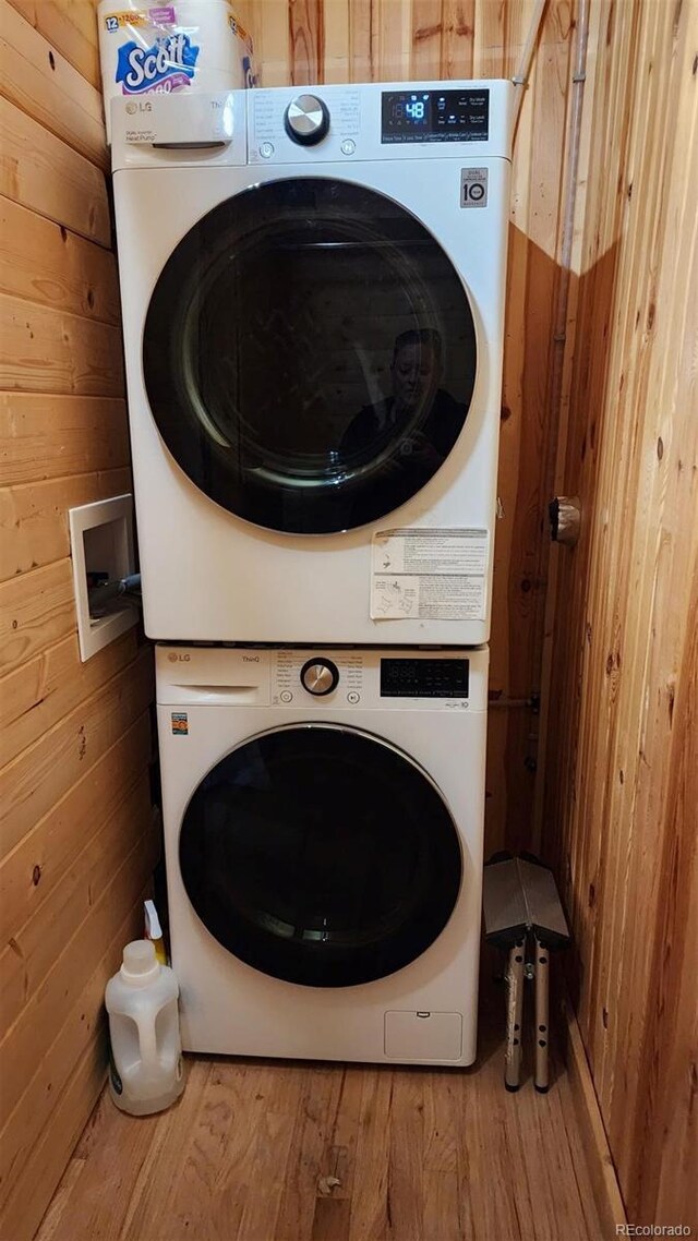256 Fisk Fenner Rd, Allenspark, CO 80510 - laundry room featuring stacked washer and clothes dryer, wood finished floors, and wood walls