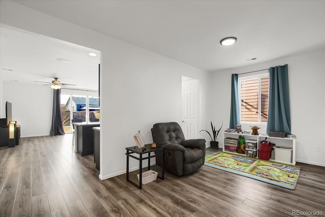 living area featuring ceiling fan, visible vents, baseboards, and wood finished floors