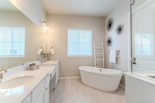 bathroom featuring tile patterned floors, a washtub, vanity, and a healthy amount of sunlight