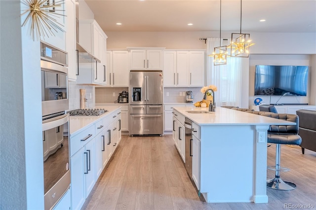 425 W 128th Dr, Westminster, CO 80234 - kitchen featuring stainless steel appliances, a sink, open floor plan, light wood finished floors, and recessed lighting