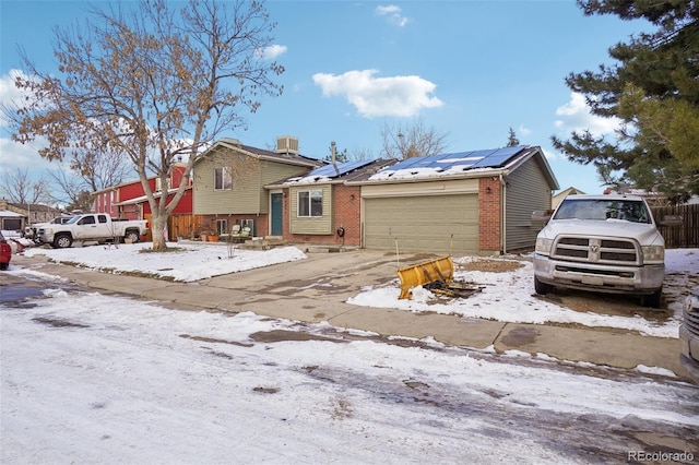 split level home featuring a garage, central AC unit, and solar panels