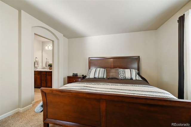 bedroom featuring connected bathroom and light colored carpet