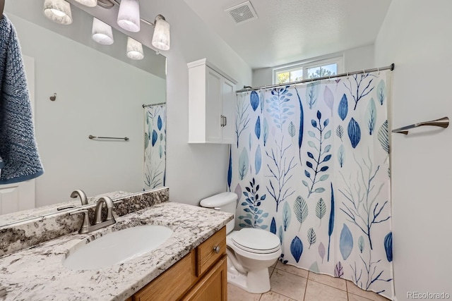 bathroom with curtained shower, tile patterned flooring, toilet, vanity, and a textured ceiling