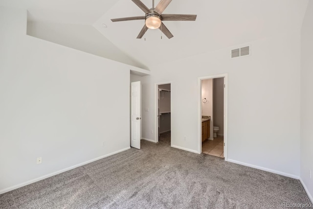 unfurnished bedroom with ensuite bath, ceiling fan, a closet, lofted ceiling, and a walk in closet